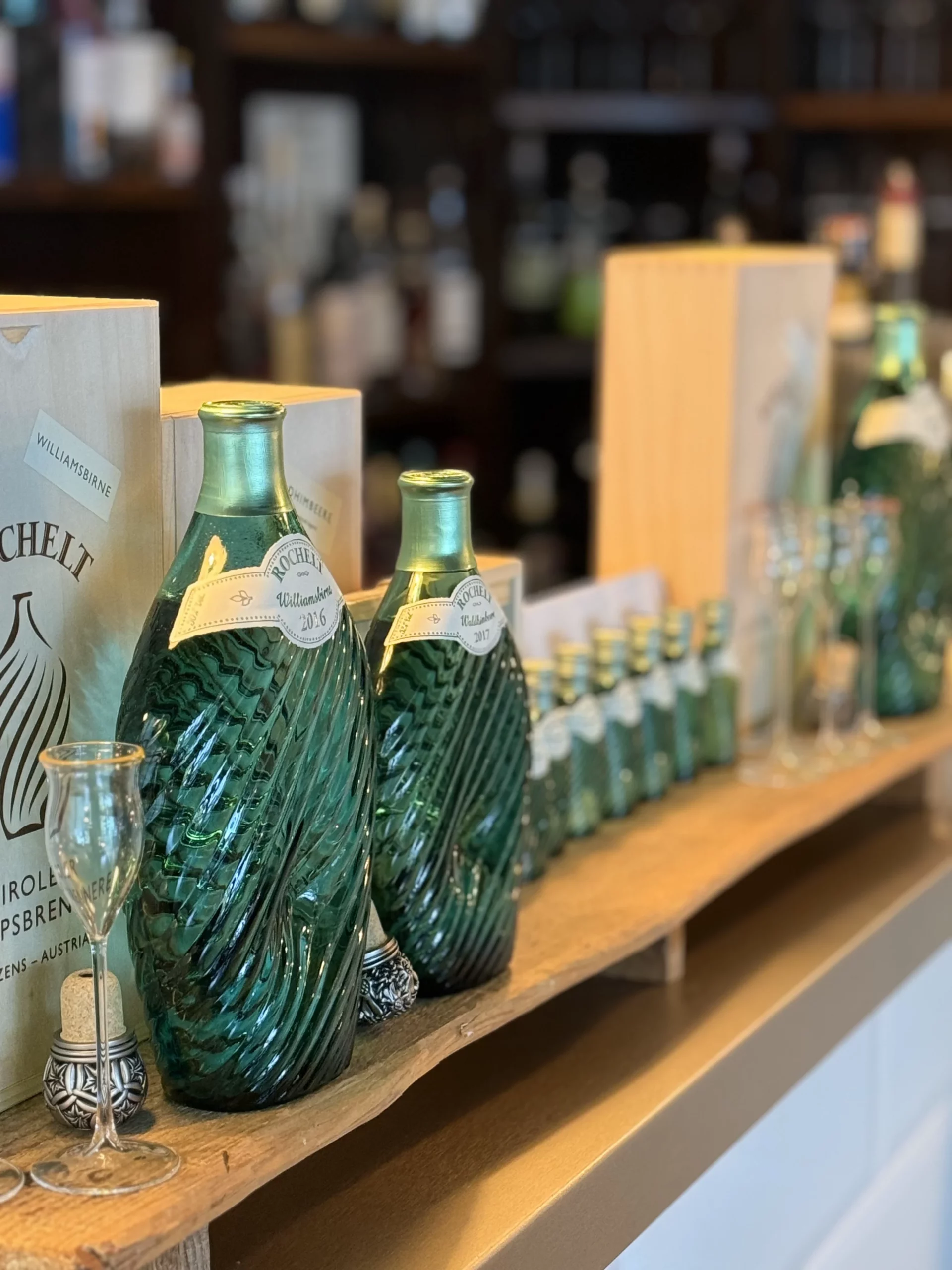 Bouteilles en verre vert et verres disposés sur une étagère en bois