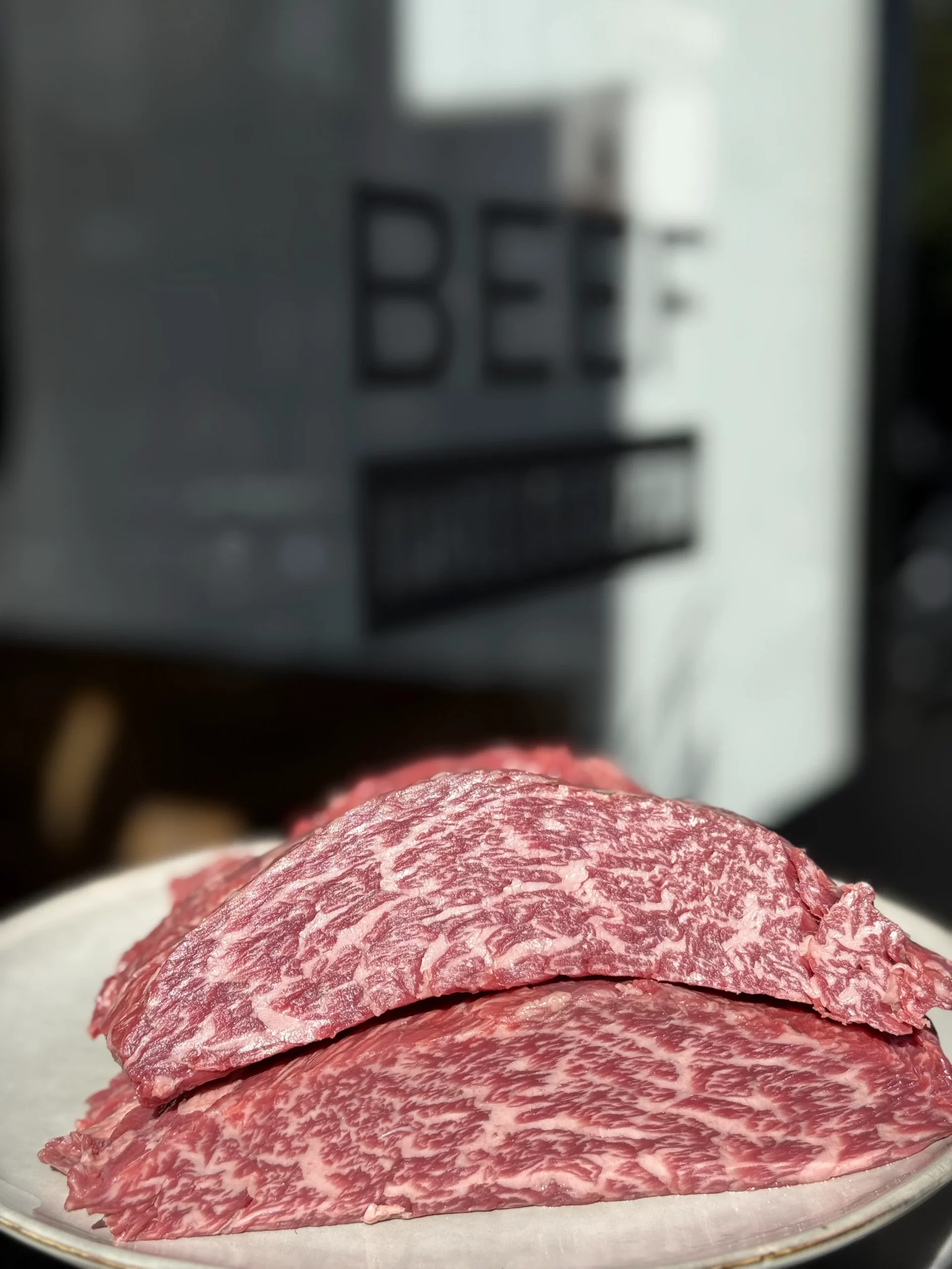 Tranches de viande crue persillée présentées sur une assiette.